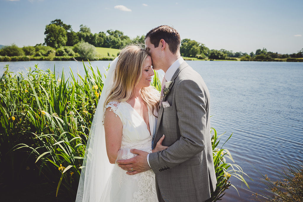 The happy couple have a romantic photo taken at the lakeside at Sandhole Oak Barn